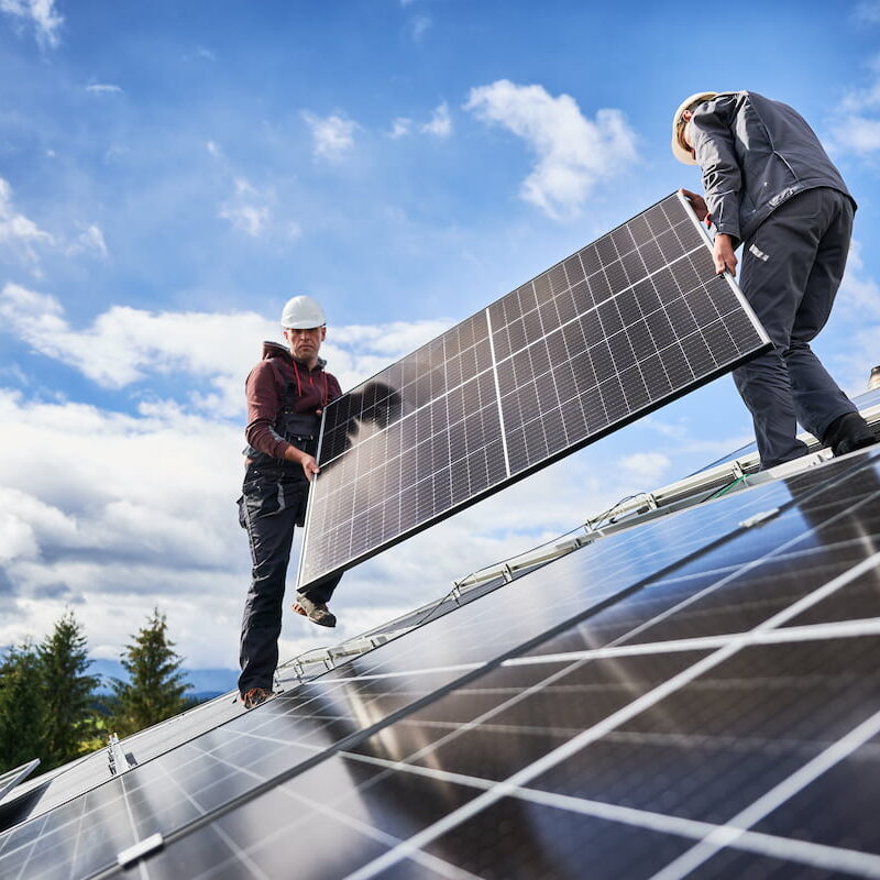 Two Solar panel installers on a roof.