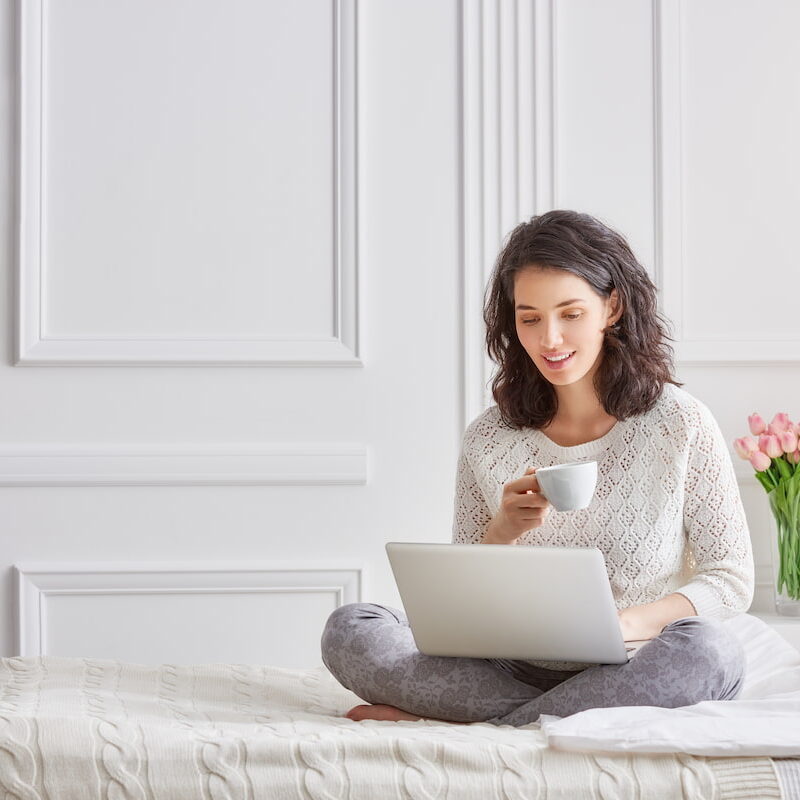 Woman on a bed looking at a computer