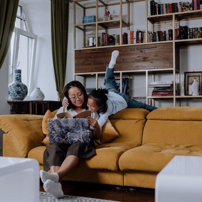 Mother and daughter acting playfully on an orange sofa in a modern home