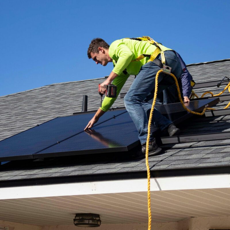 Man installing a solar panel on a roof